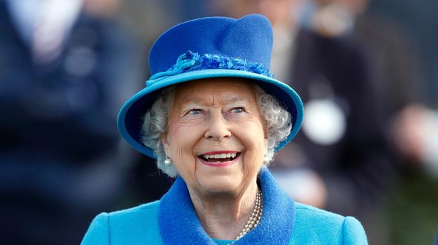 Queen Elizabeth II smiling brightly, wearing a bright blue outfit and hat