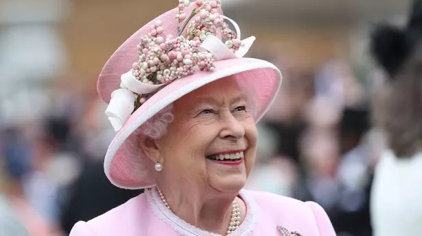 The late Queen Elizabeth smiling and dressed in pink