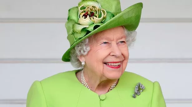 The late Queen Elizabeth II smiling, wearing a lime green outfit